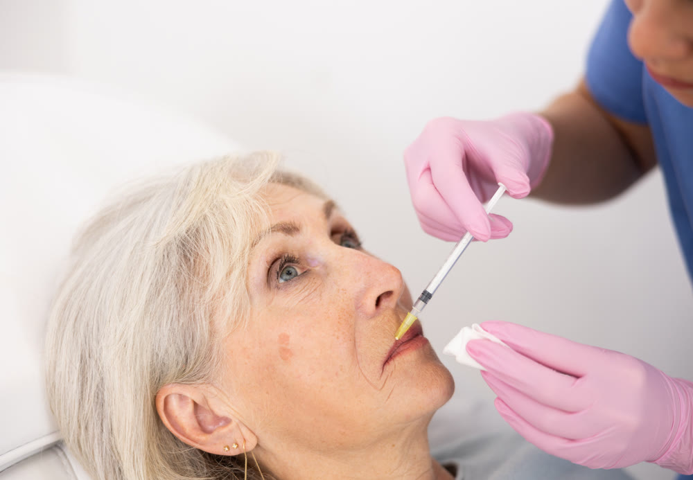 Old woman having mesotherapy procedure on her face
