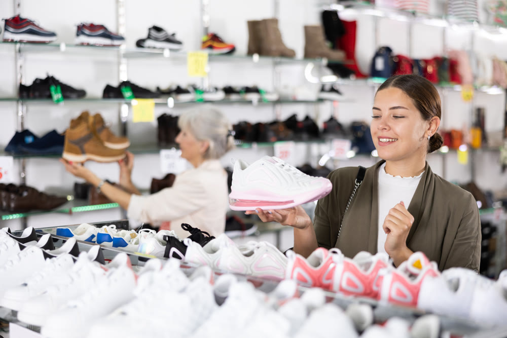 Woman holding desired shoe in hands in fashion boutique