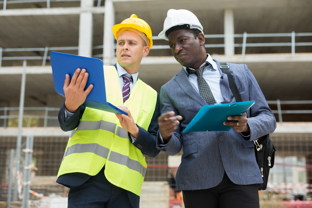 Architect and foreman must write documents and drawings on laptop with building construction