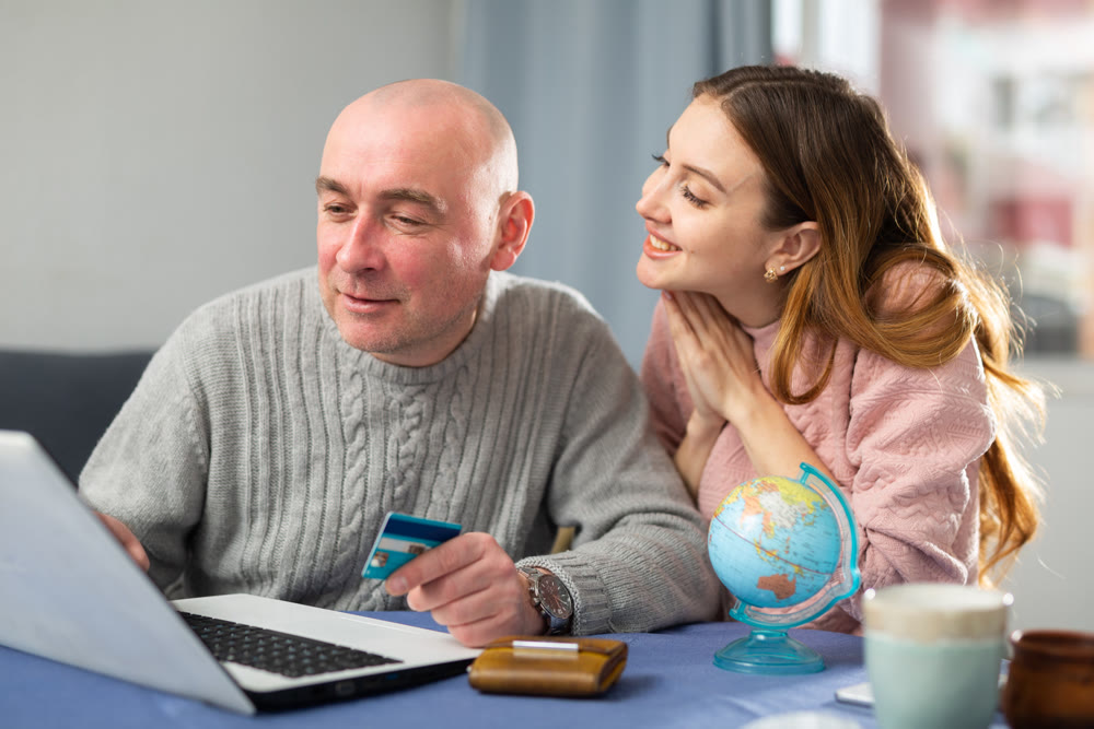 Happy married couple book a vacation tour on a laptop