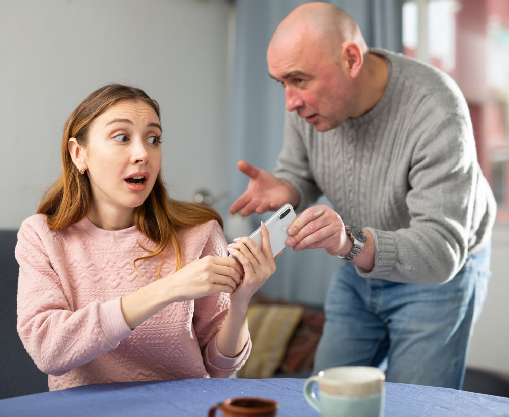 Amazed woman trying to don't give away her phone to her jealous husband