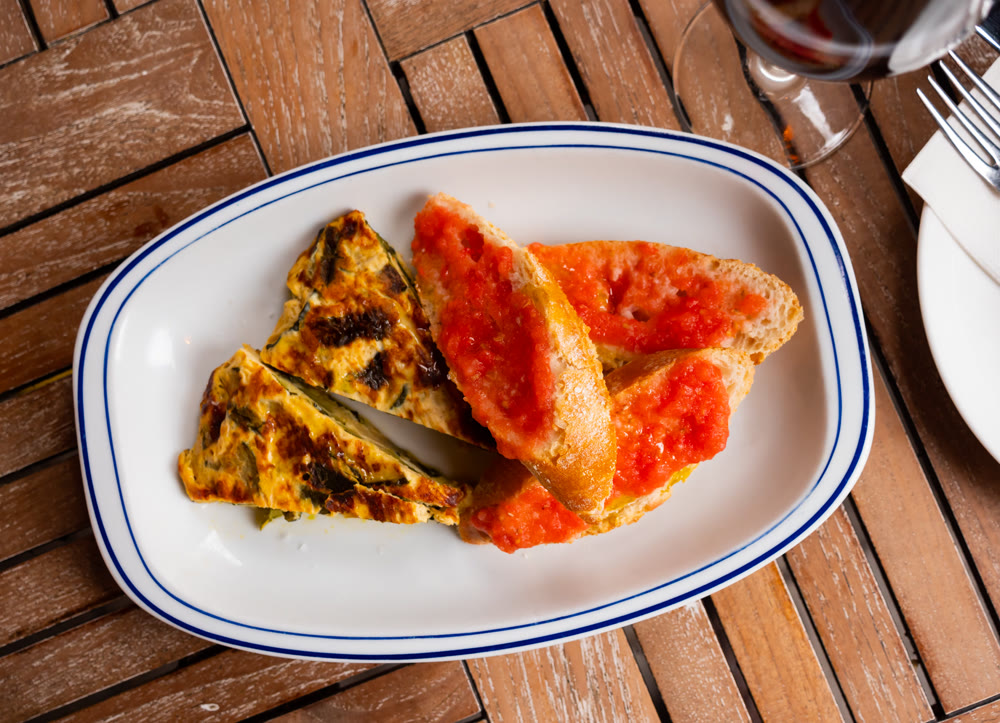Zucchini tortilla skewer and bread with tomato pulp. Spanish dish closeup