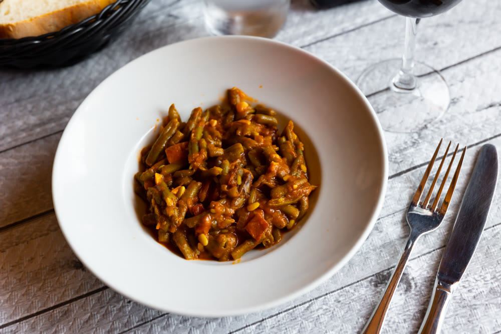 Dish of green beans with ham and tomatoes
