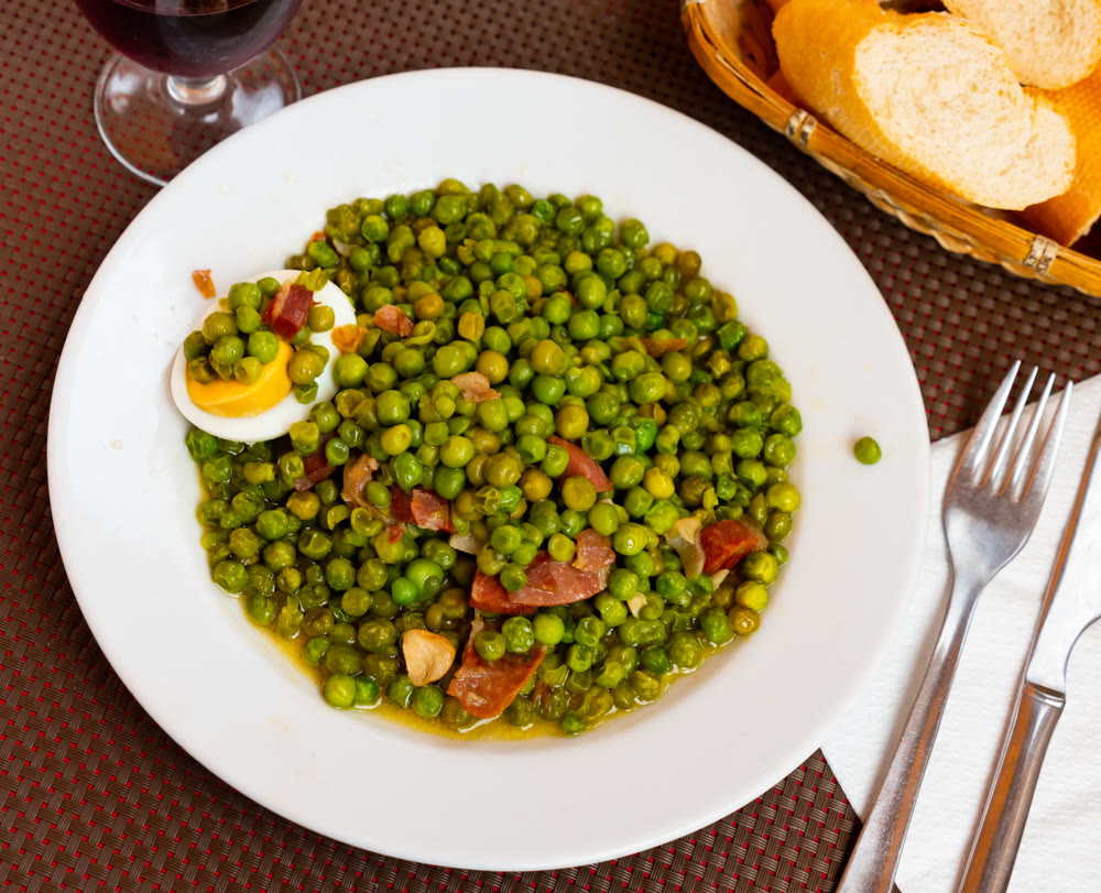 Just cooked green peas with ham and egg on plate