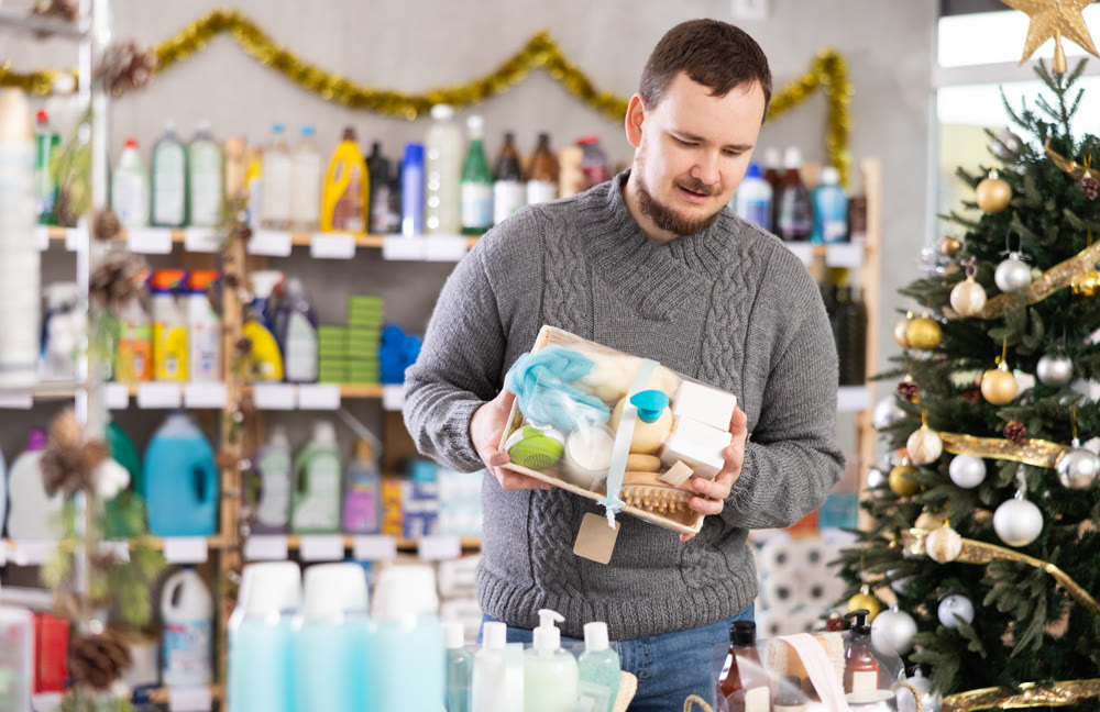 Interested nice bearded man choosing gifts for New Year in household department of supermarket