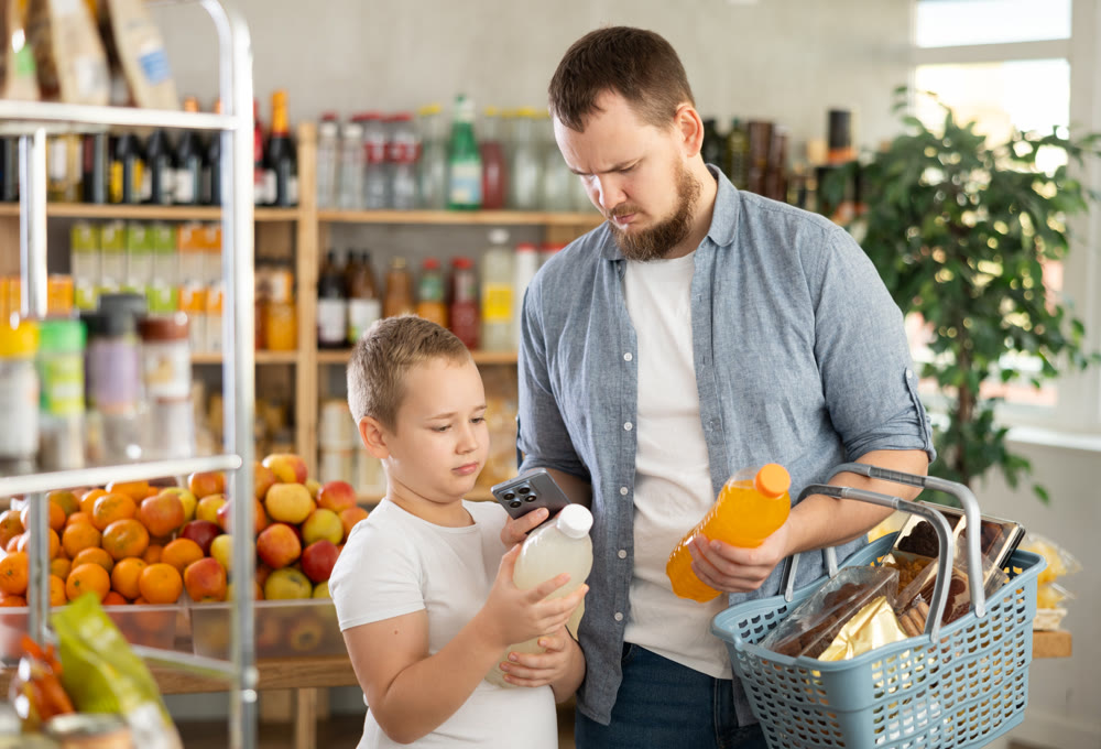 Man with preteen son scanning barcode on drink bottles in grocery store