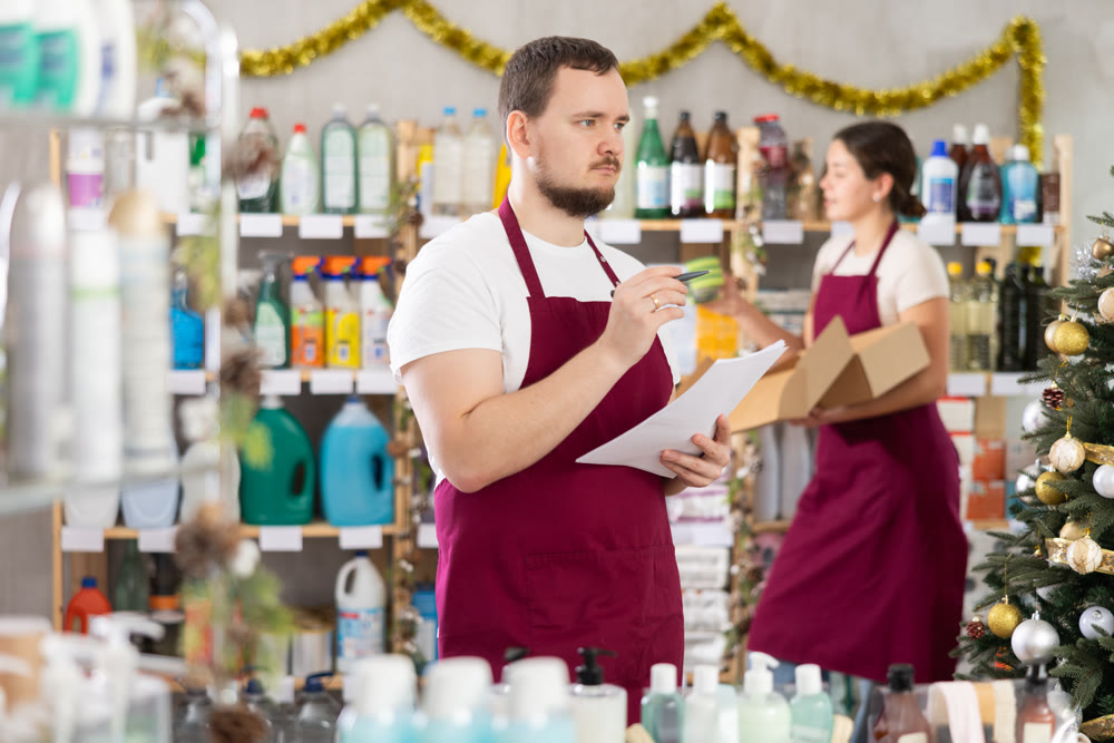 Man seller with woman assistant taking inventory in store