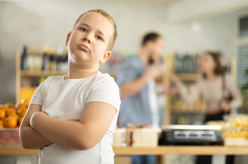 Portrait of capricious offended boy against the backdrop of arguing parents - family quarrel in grocery store