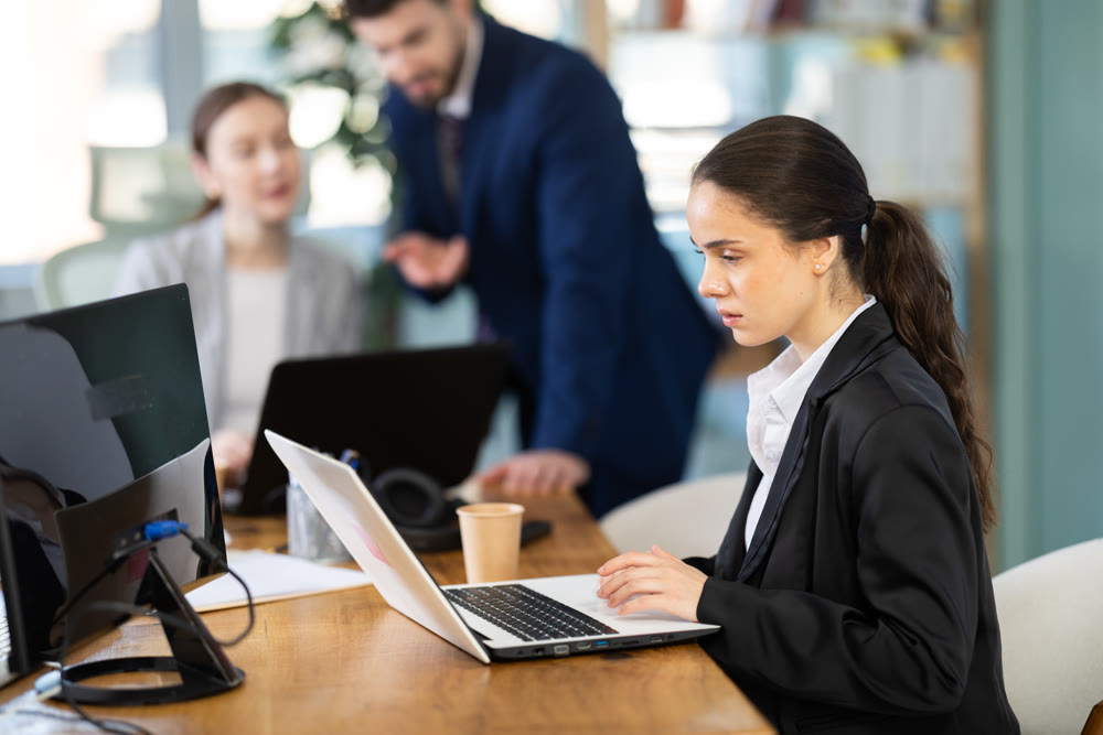 Focused young woman working on laptop during busy corporate session