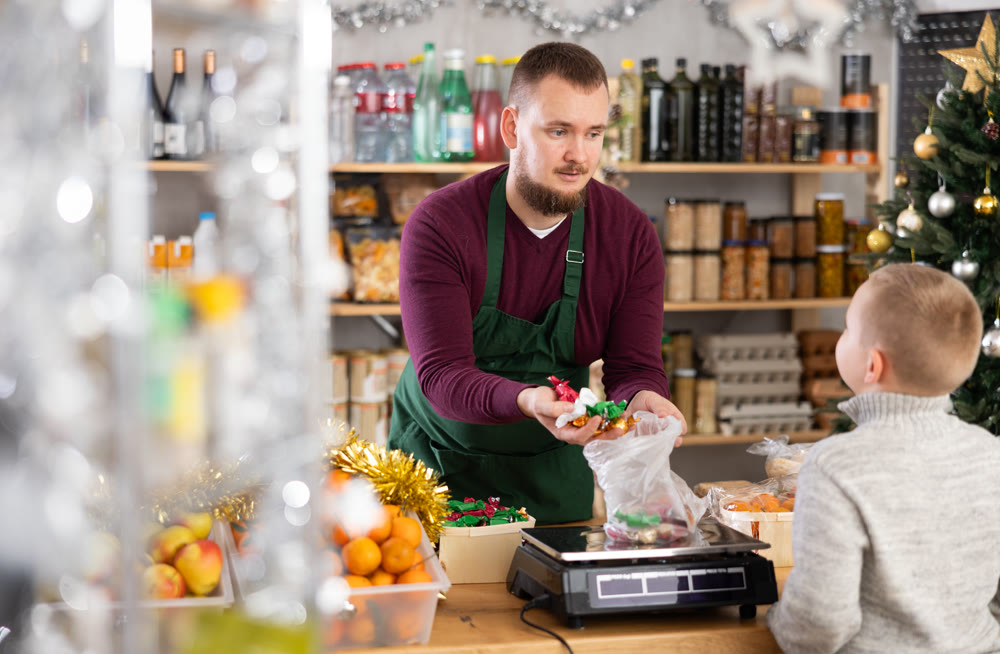 Man seller weighs candies for boy buyer