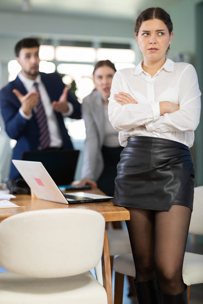 Group of people scolding sad colleague sitting at laptop in office