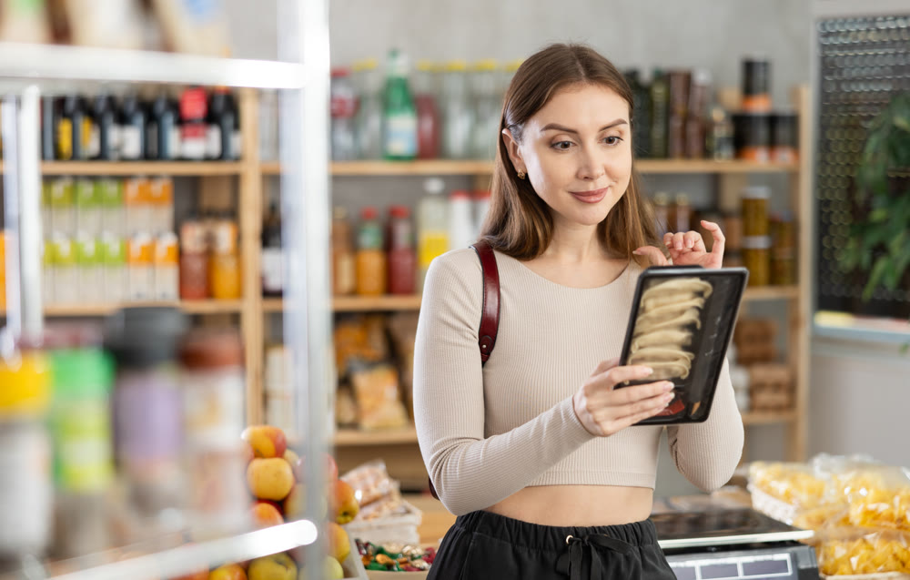 Young woman choosing jiaozi at grocery store