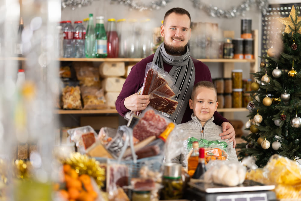Father and son standing in festive market with chosen products in hands