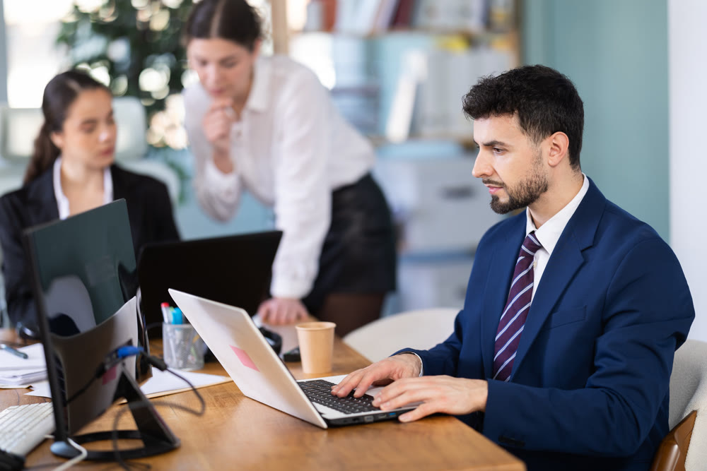 Focused young man working on laptop during busy corporate session