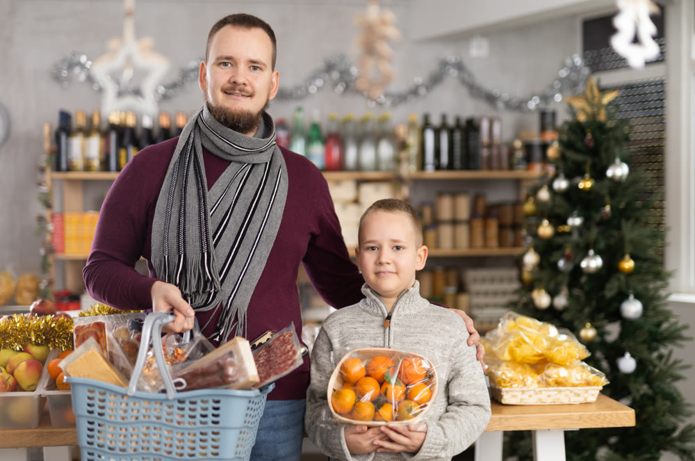 Father and son standing in festive market with chosen products in hands