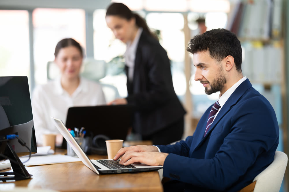 Focused young man working on laptop during busy corporate session