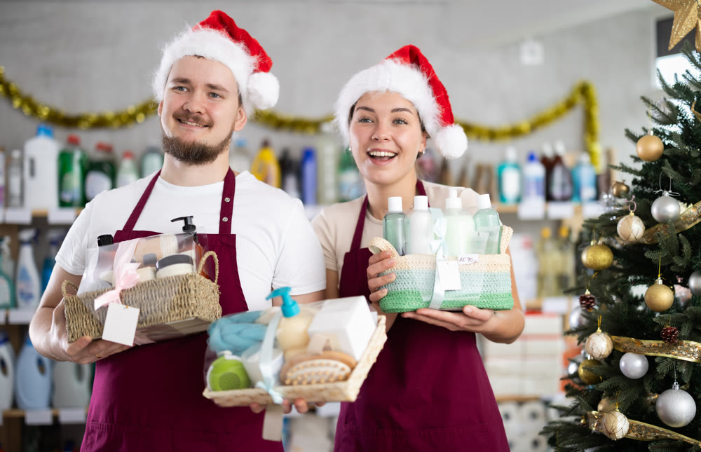 Cheerful sellers in Santa hats offering cleaning supplies and toiletries in store