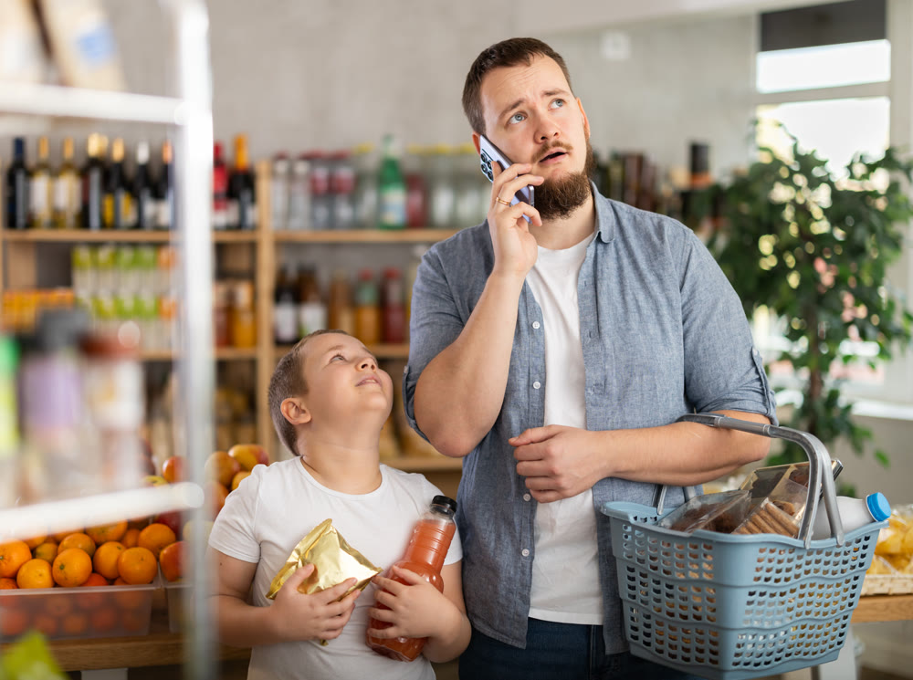 Dad and son, while shopping for groceries, call up with mom, discuss on phone purchase of snacks