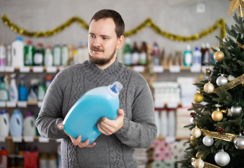 Man choosing detergent while shopping in Christmas decorated store