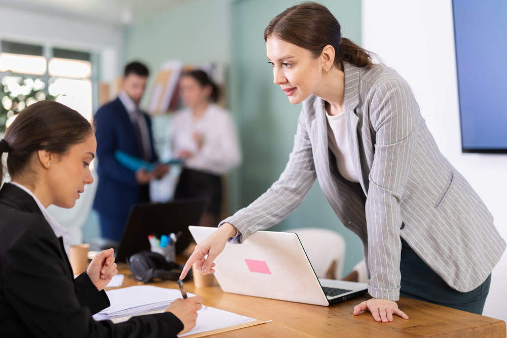 Employee helps an intern with documents against the background of the office