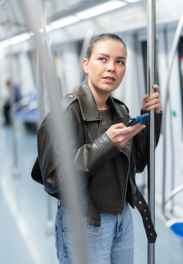Girl stands in subway car and writes message on her smartphone screen