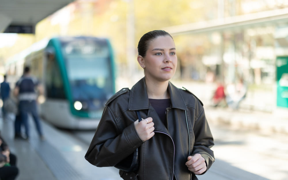 Pretty girl walks along the platform waiting for tram