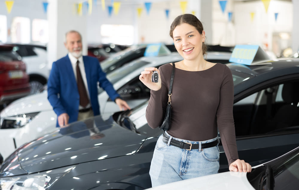 Young woman is happy to buy a car, she keeps the keys