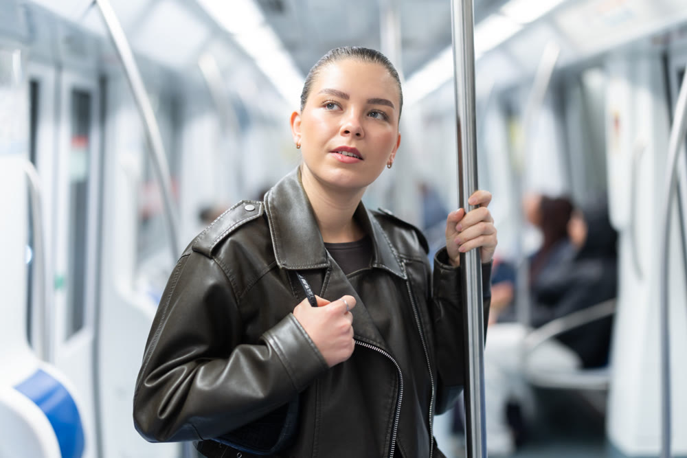Cute girl holds onto handrail while riding in subway car