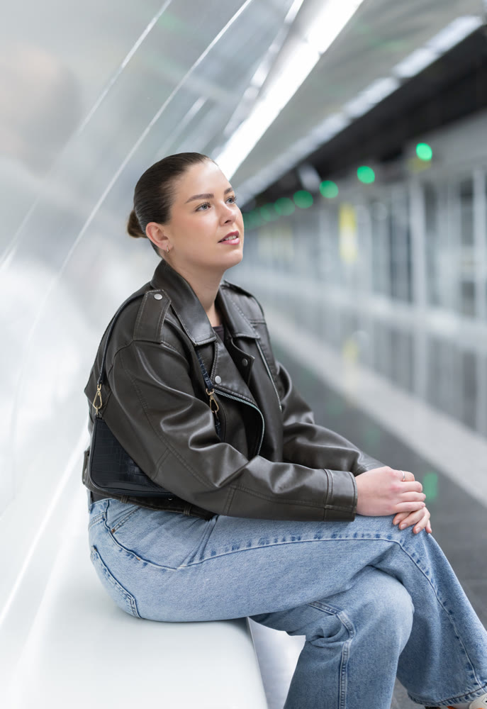 Portrait of pretty girl sitting on bench waiting for subway train