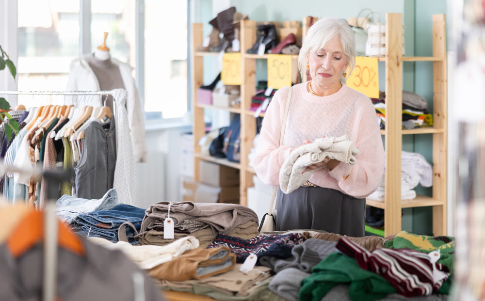 Elderly woman chooses sweater in clothing store