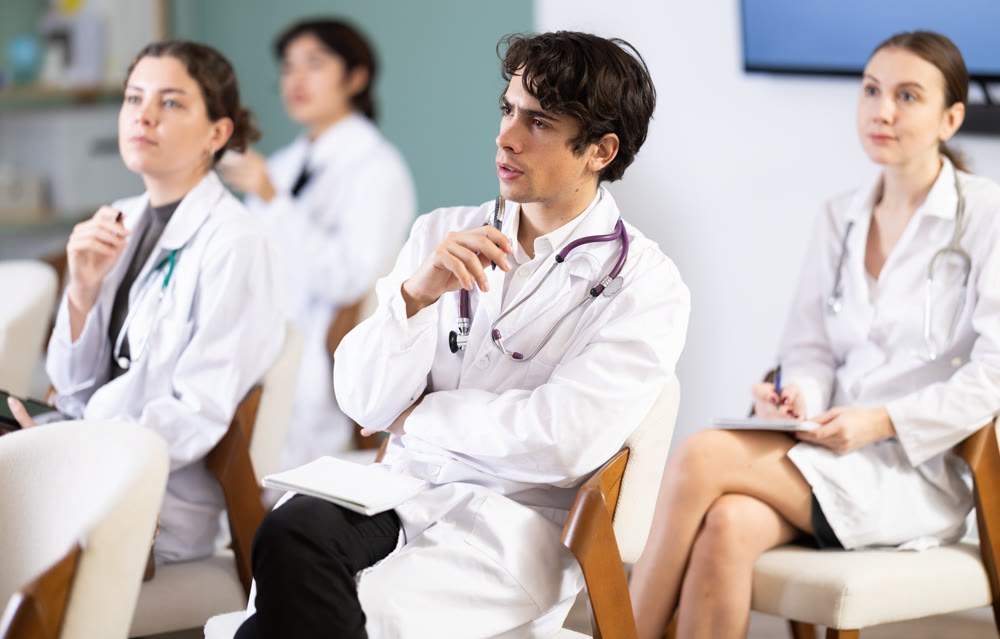 Young female doctor listening and taking notes in lecture hall