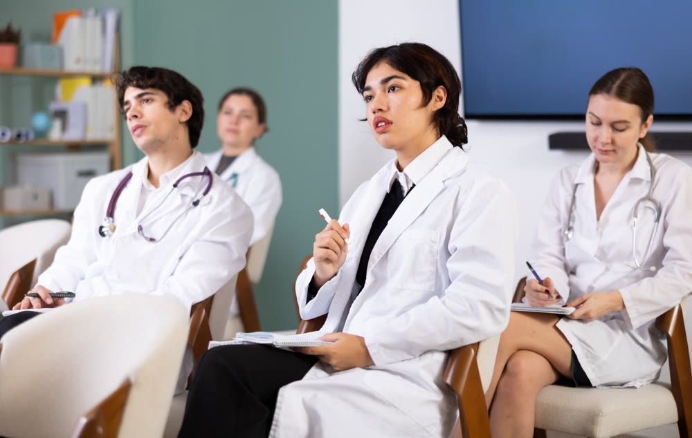 Focused malaysian girl medical student sitting on chairs and listening lecture in lecture hall
