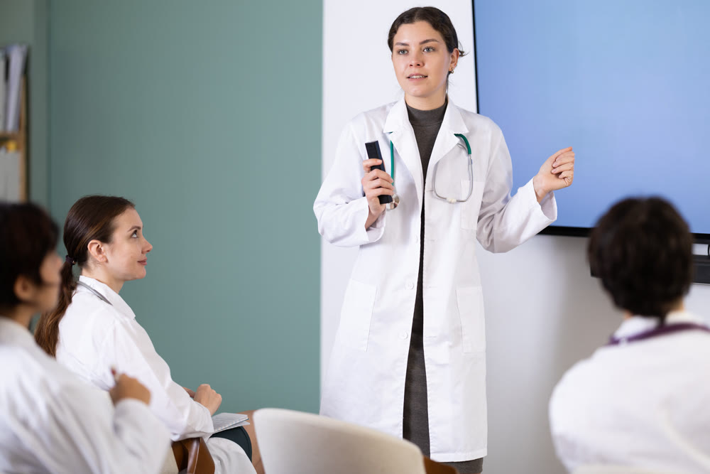 Young female doctor presenting with remote control in meeting room