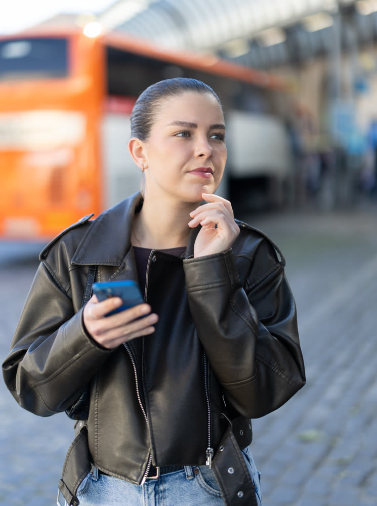 Joyful woman with a phone in hands walks around city, she looks at maps in mobile application