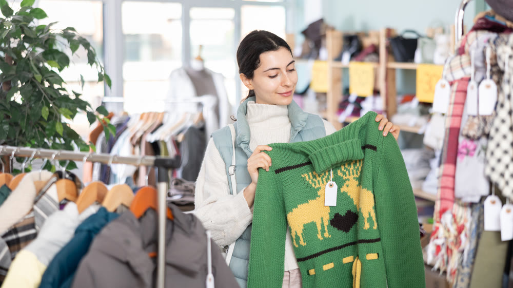 Girl chooses fashionable sweater in clothing store
