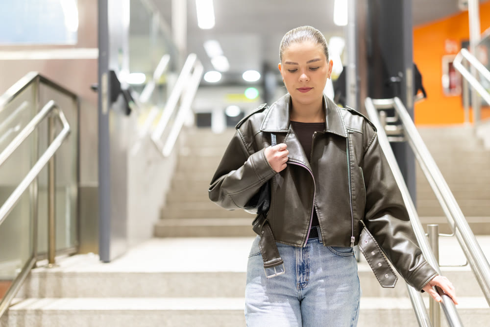 Girl in black leather jacket walks down the stairs to metro station