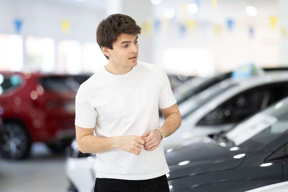 Guy carefully chooses a car in a car dealership