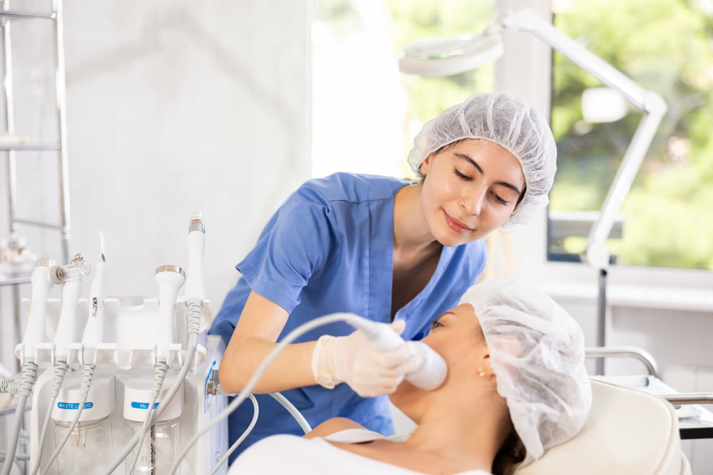 Young woman cosmetologist doing whitening procedure to young woman
