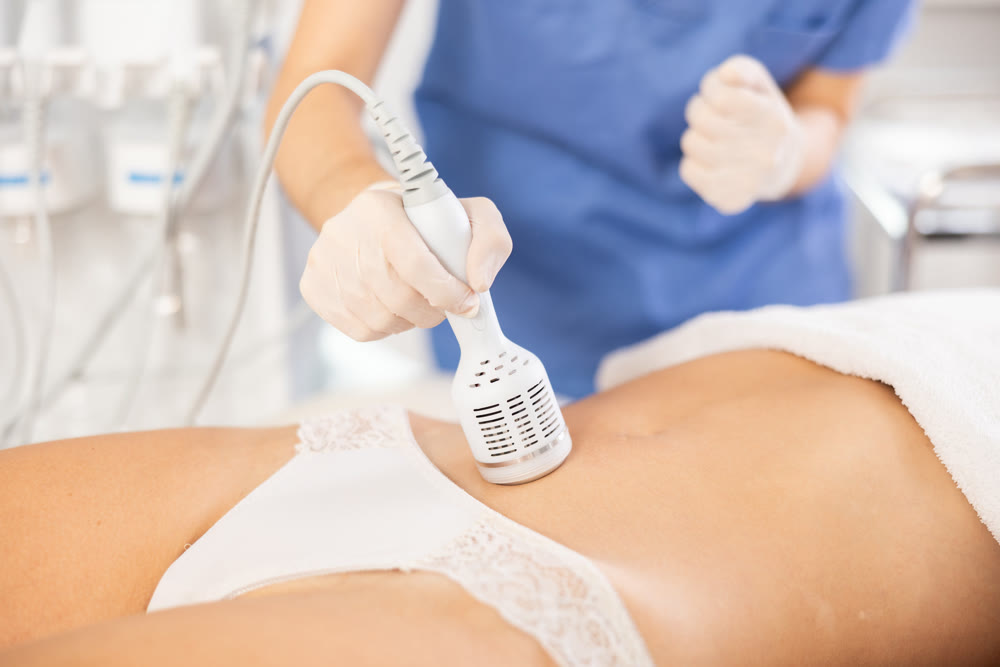Aesthetician administering cold hammer therapy on female client belly