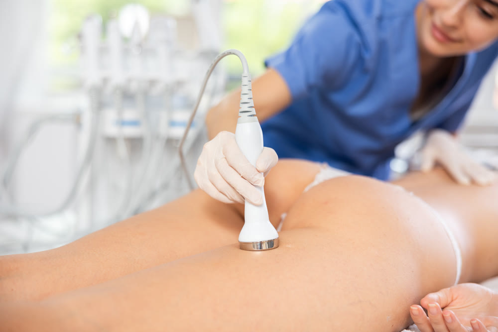 Cosmetologist performing high-frequency ultrasound procedure on female buttocks