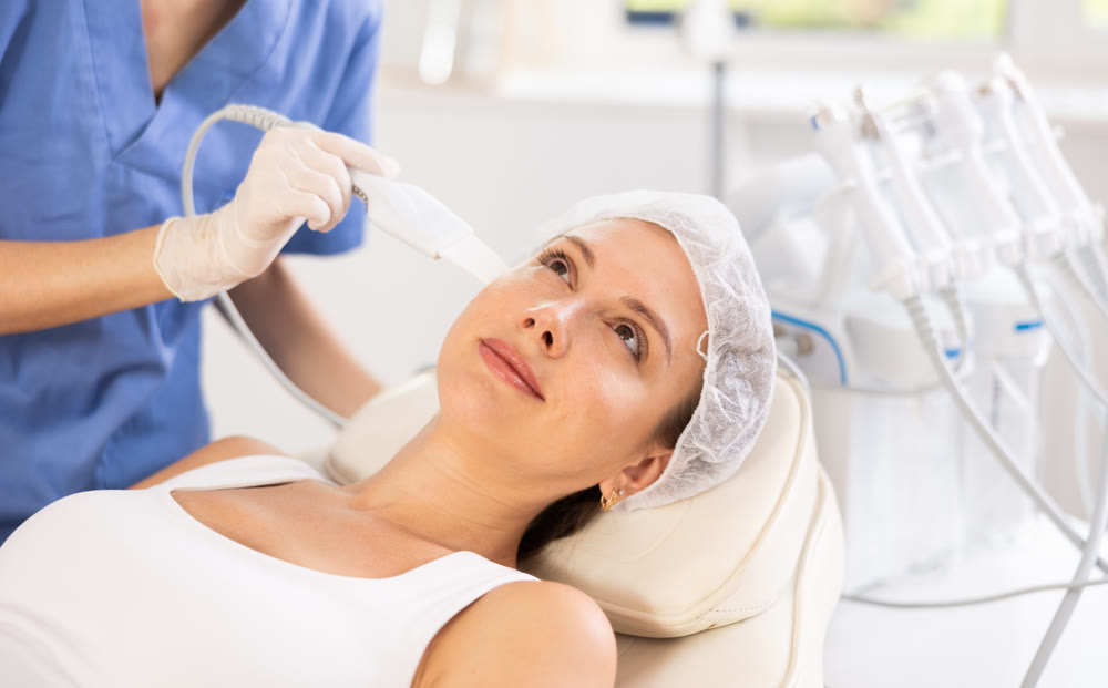 Young woman undergoing facial cleansing procedure using ultrasonic shovel