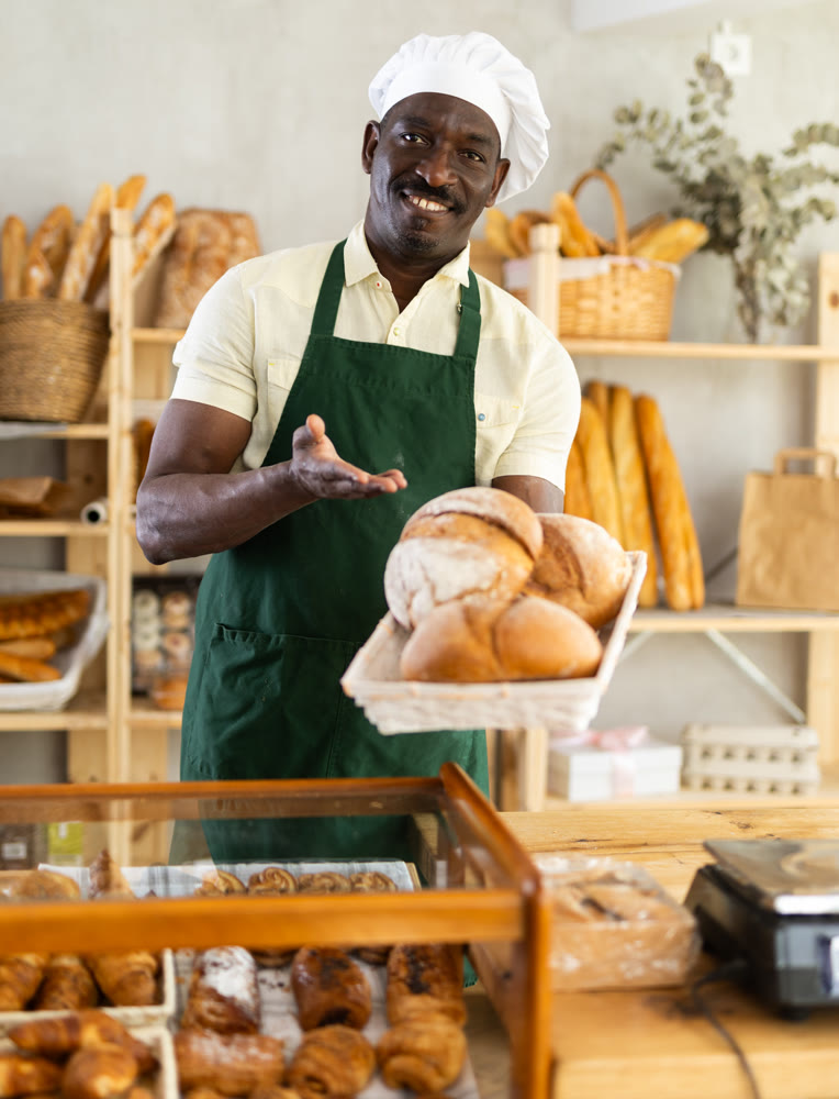 Portrait of male baker with bread and baguettes in hands in bakery