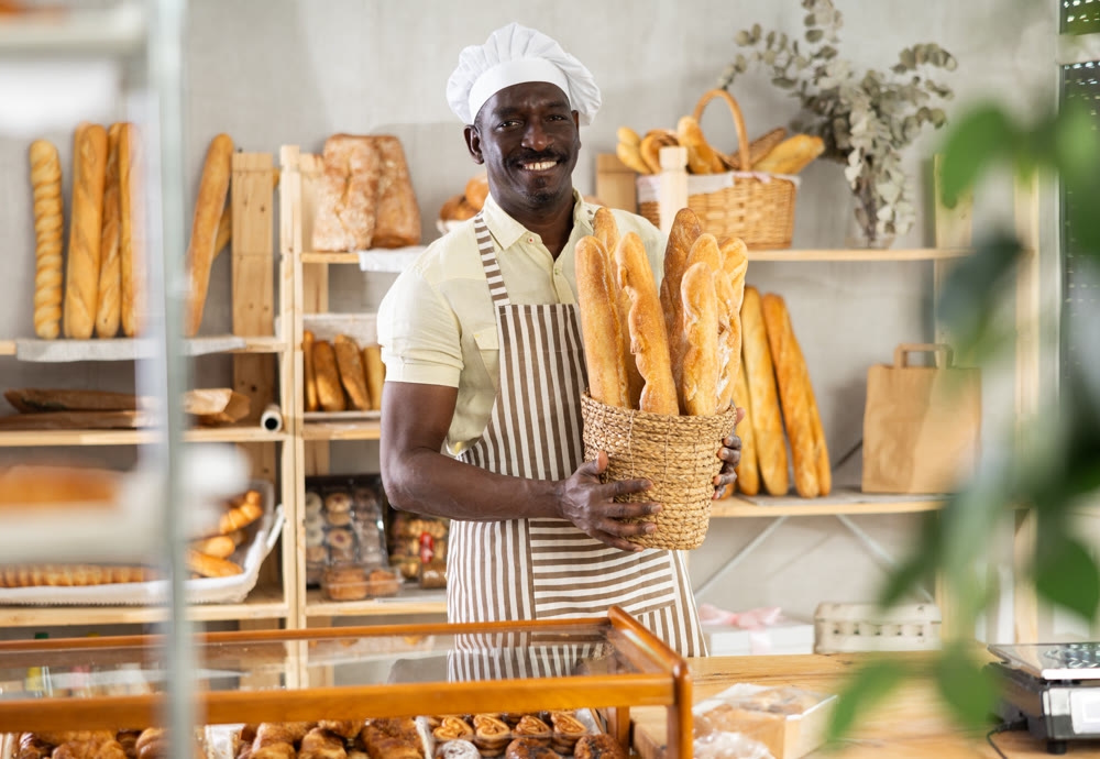 Portrait of joyful man baker with baguettes