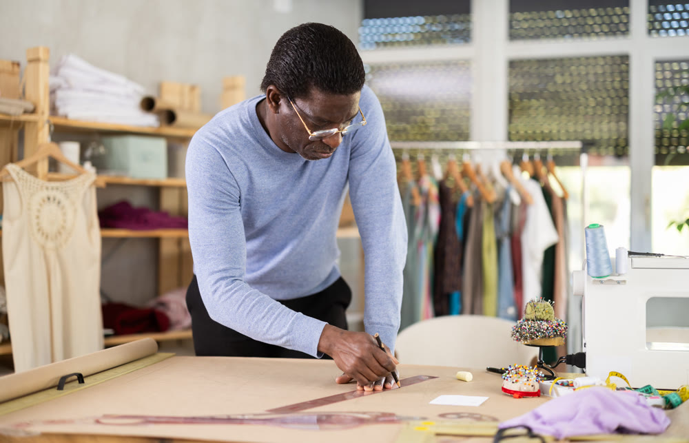 African American man tailor draw dress pattern of product on paper