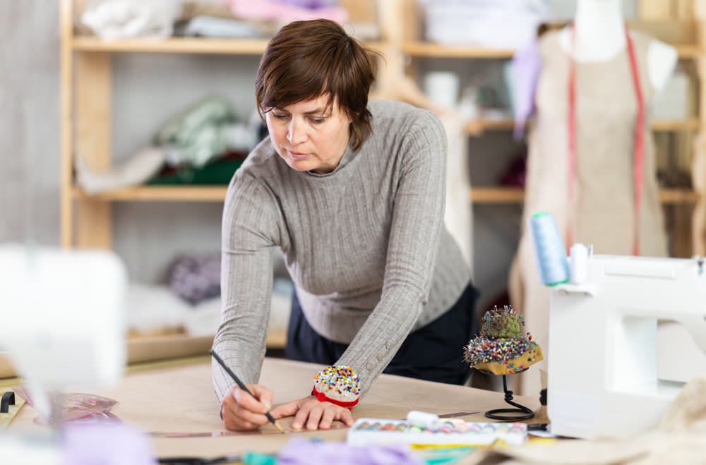 Woman tailor draw dress pattern of product on paper