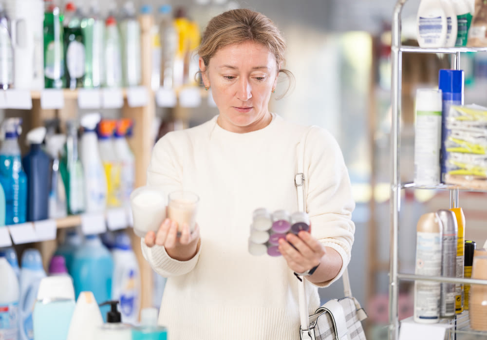 Female shopper chooses scented candles in supermarket for romantic evening