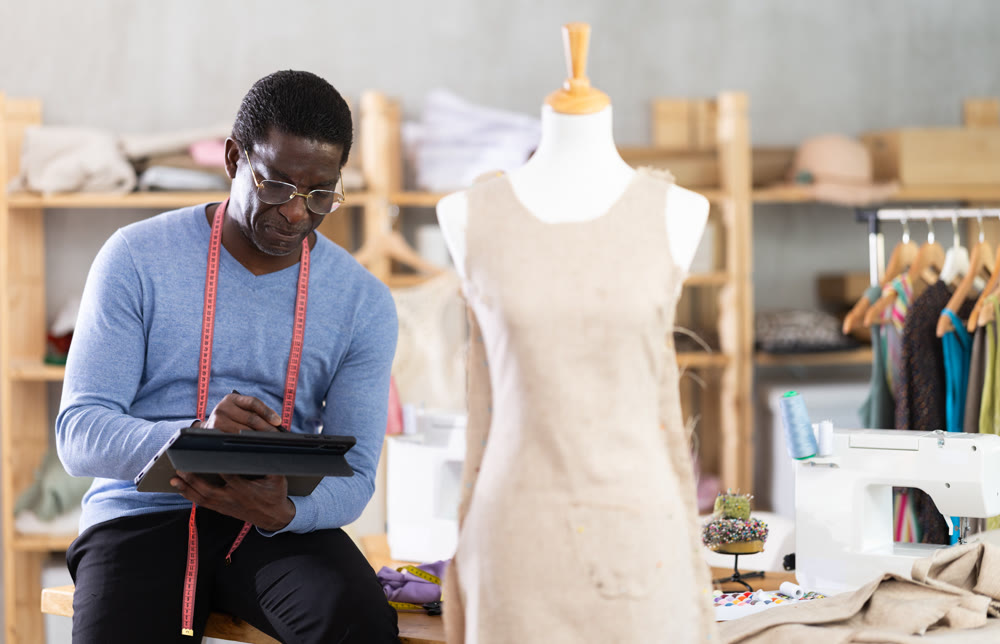 Male dressmaker working on digital sketch of dress in workshop