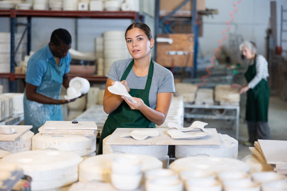 Happy female sculptor checks quality of designer clay plates