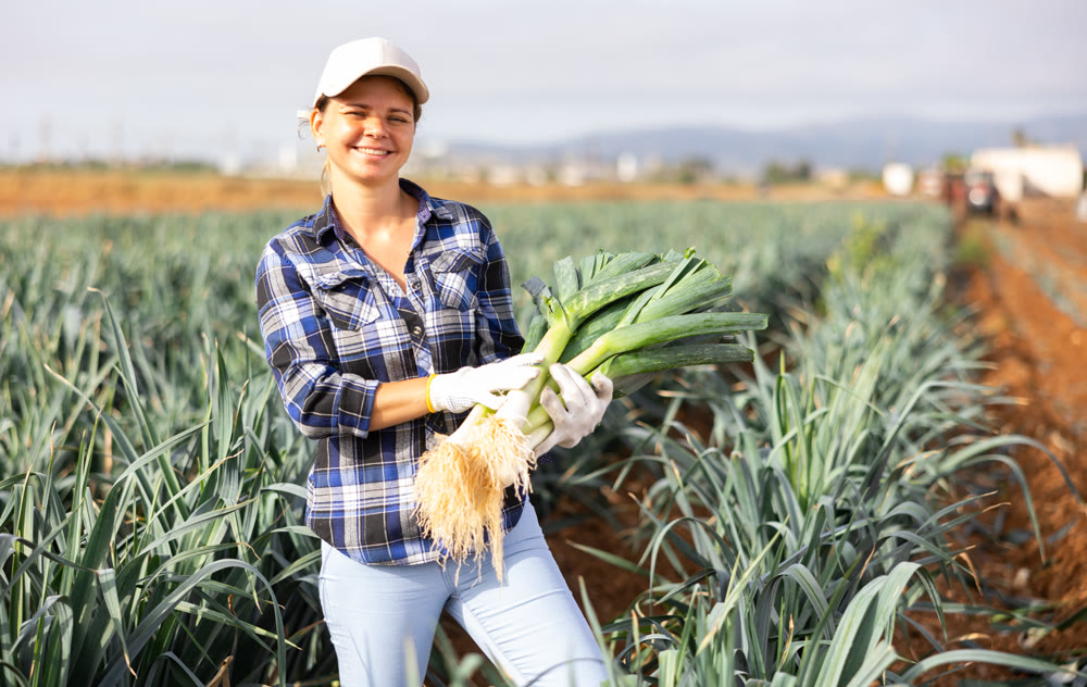 Woman posing with leek crop on field