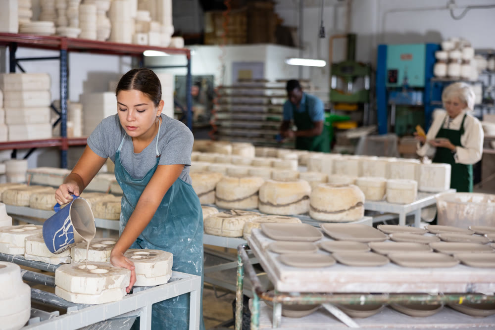 Pouring slip mass into plaster molds at pottery factory